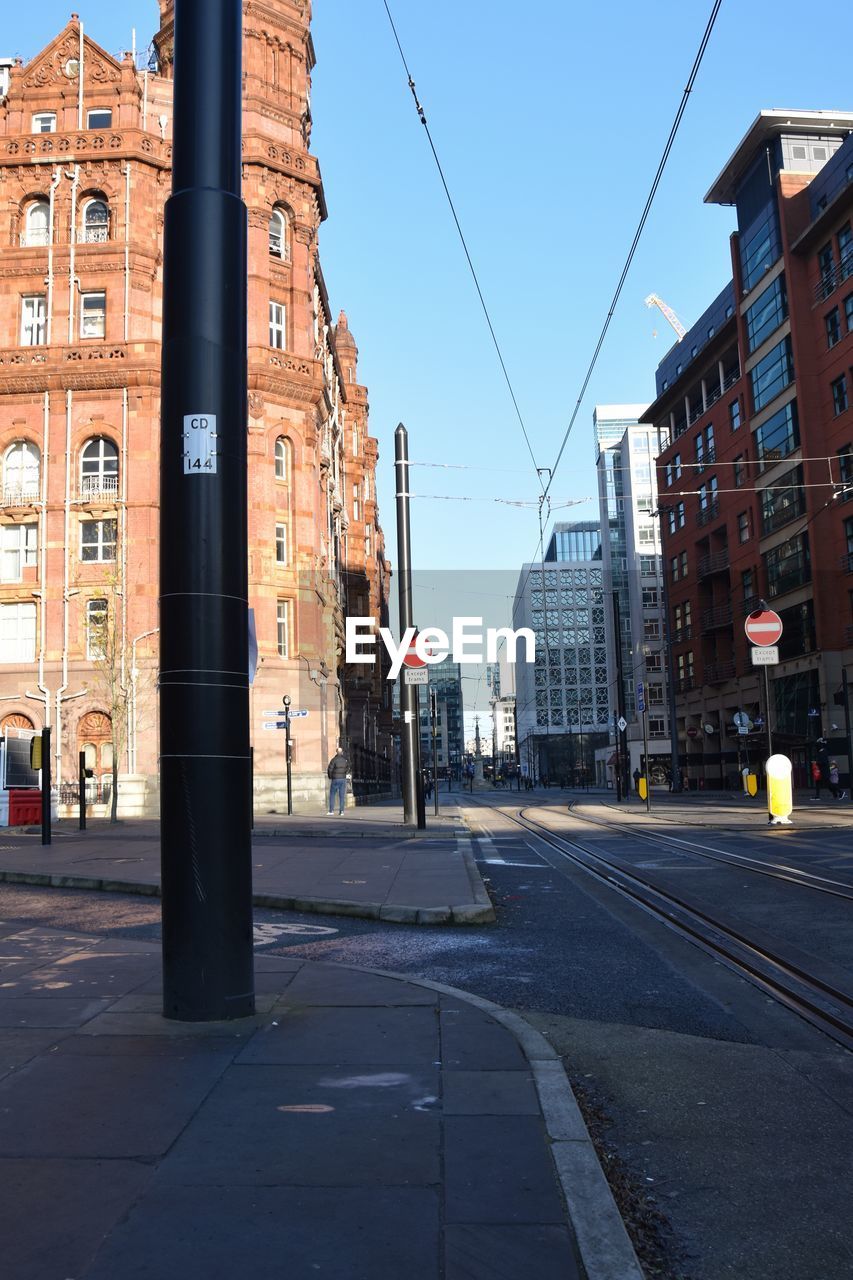 Road by buildings against sky in city