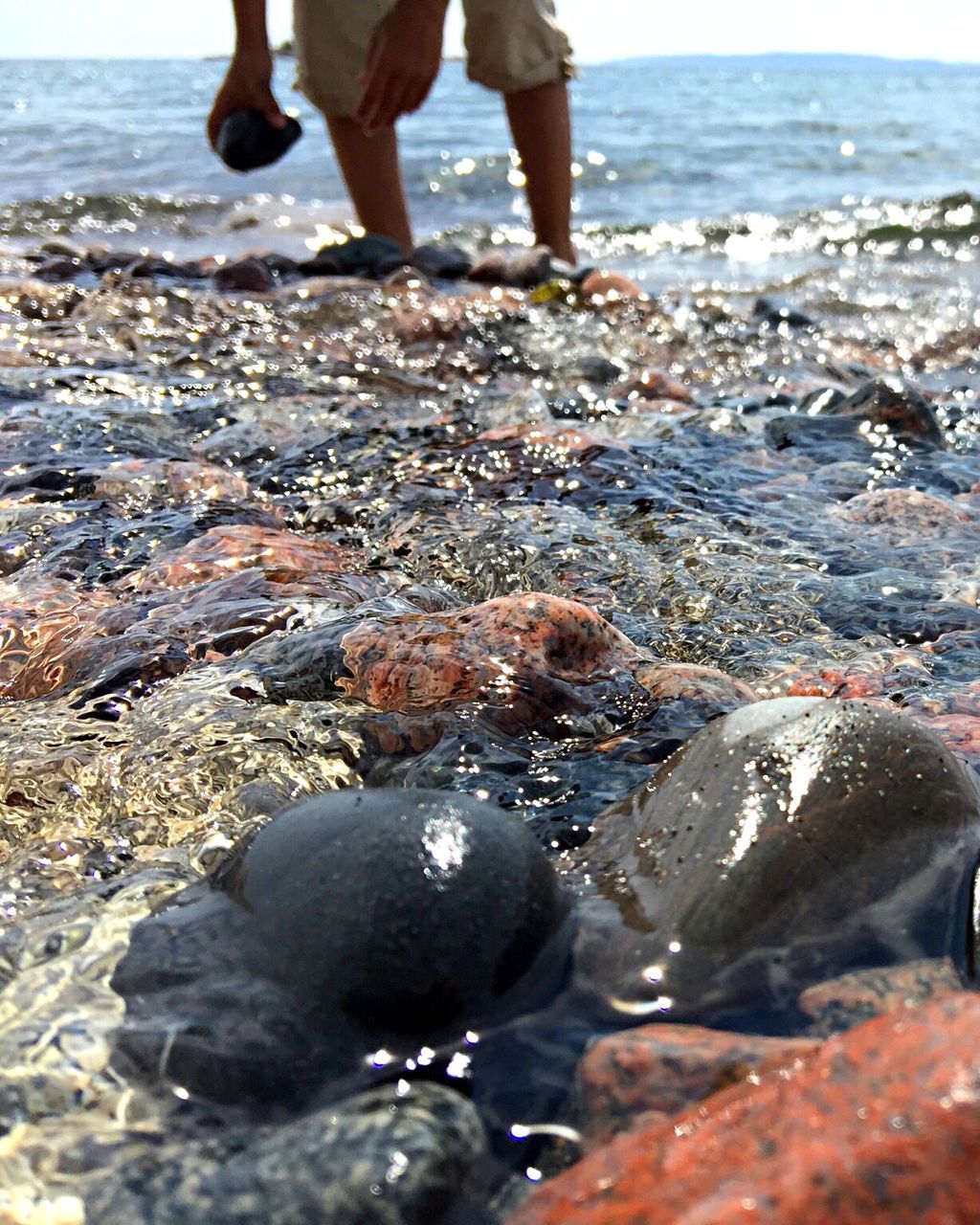 LOW SECTION OF PERSON STANDING ON SHORE