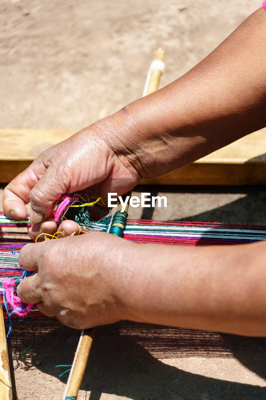 Cropped image of woman making craft on field