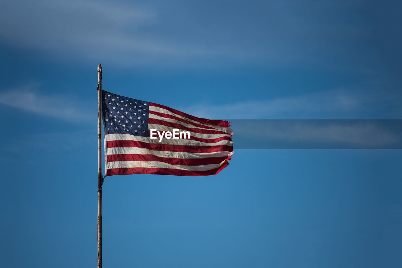 Low angle view of american flag against blue sky