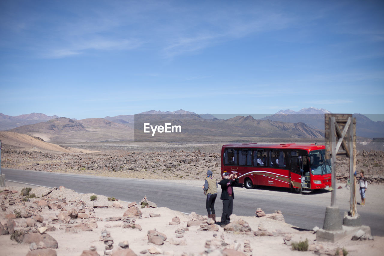 Tourists photographing on dry landscape in front of bus