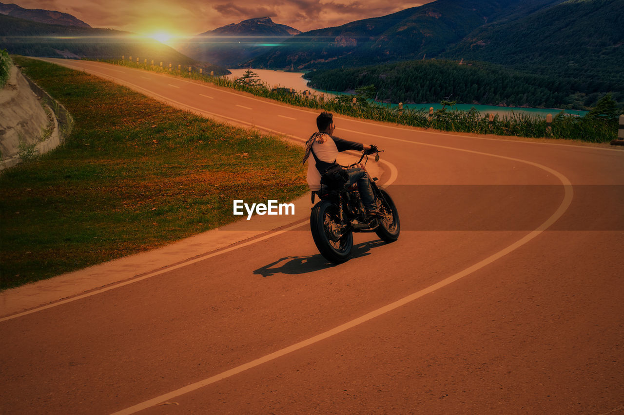 MAN RIDING MOTORCYCLE ON ROAD