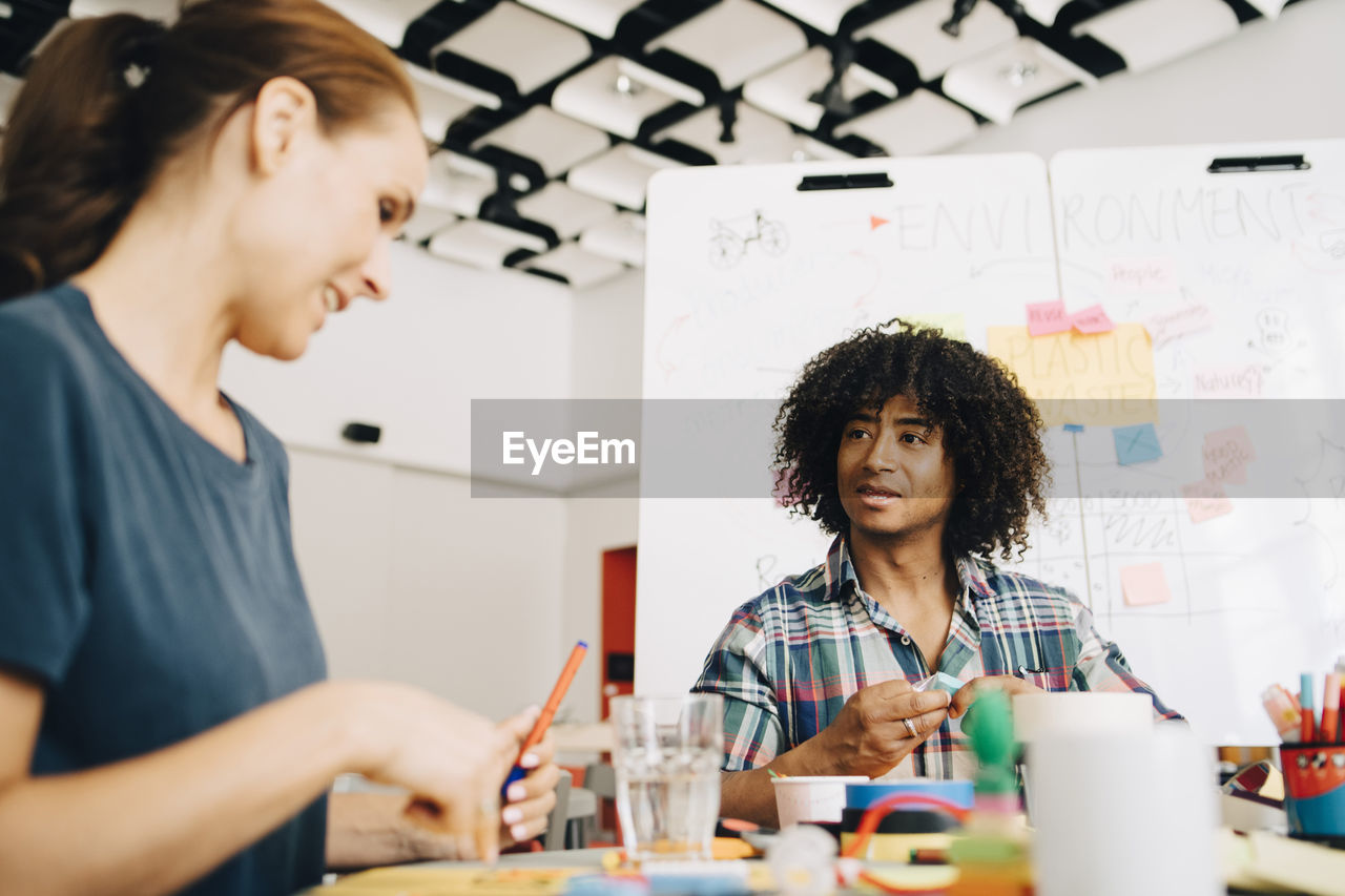 Multi-ethnic business colleagues discussing while working at table in creative office