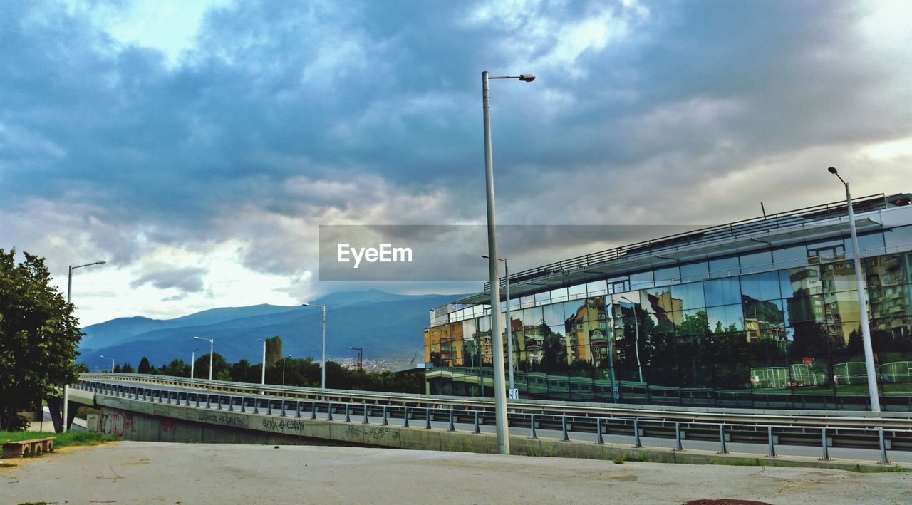 Glass building against cloudy sky