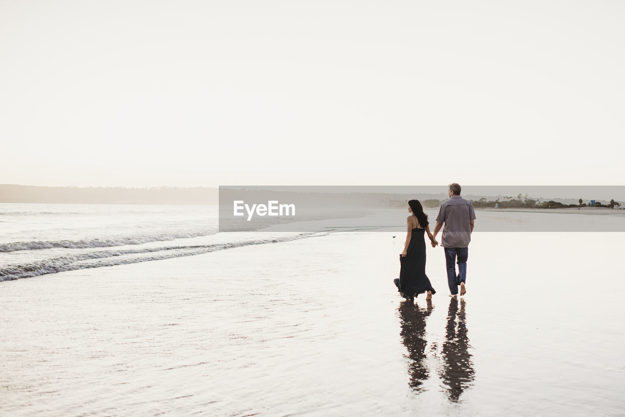 Romantic couple holding hands walking in the surf