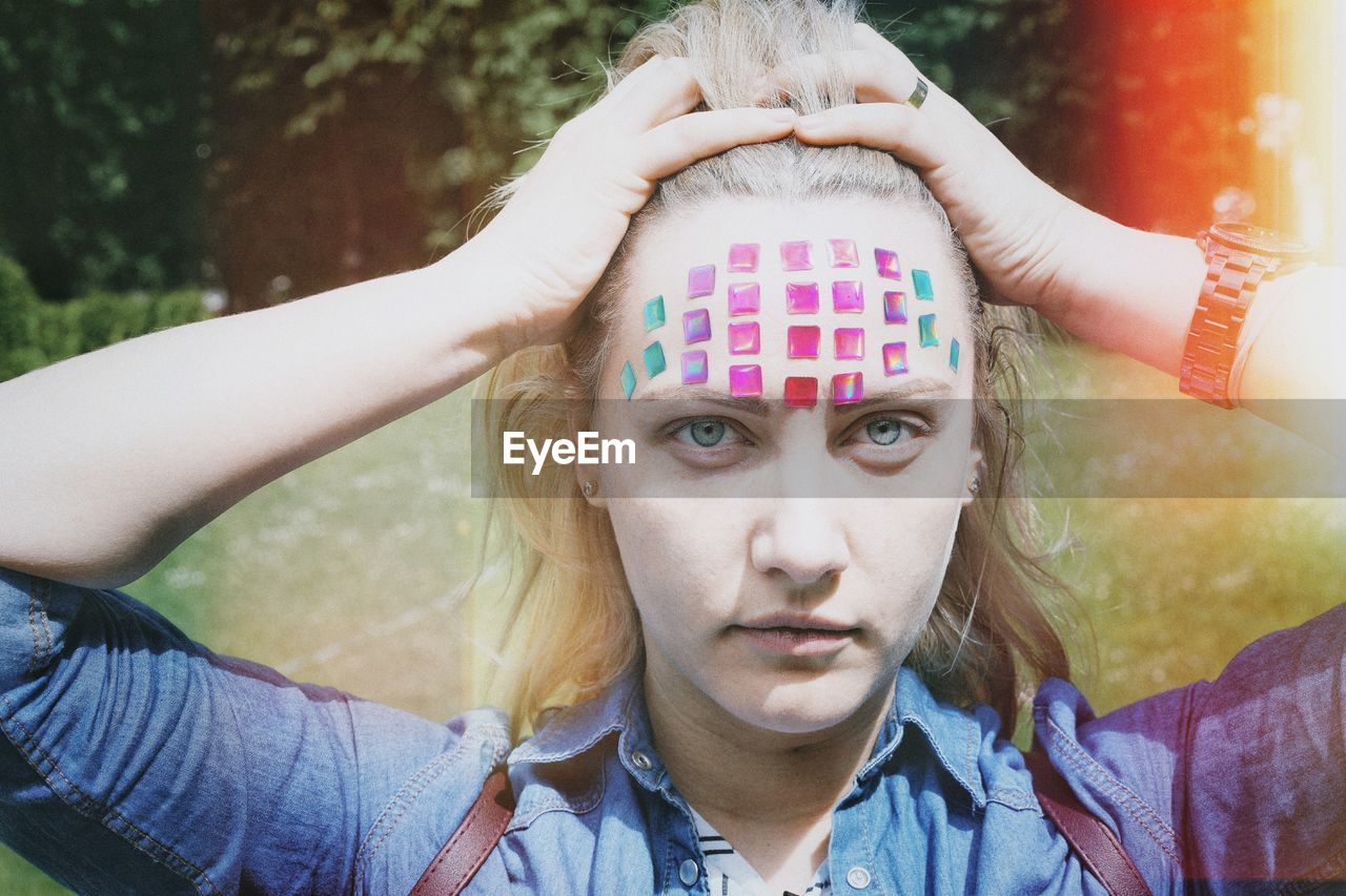 Close-up portrait of mid adult woman with colorful stickers on forehead