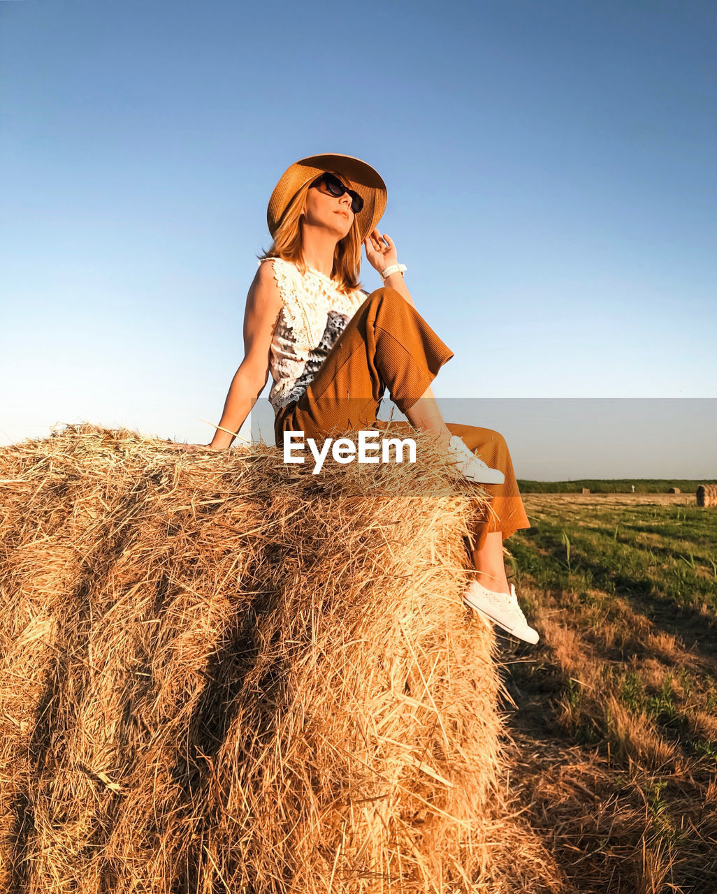 Rear view of woman wearing hat on field against sky