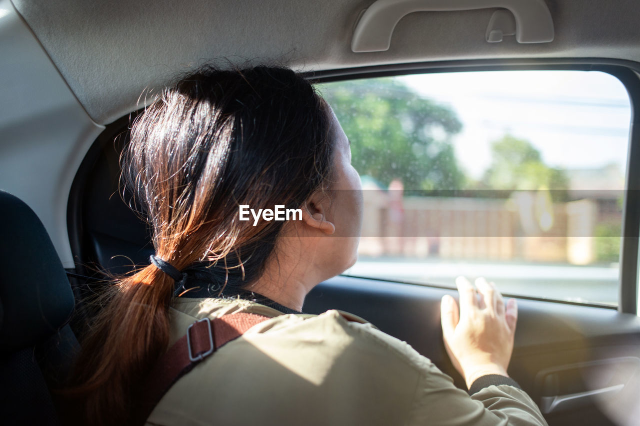 Young woman looking through window in car