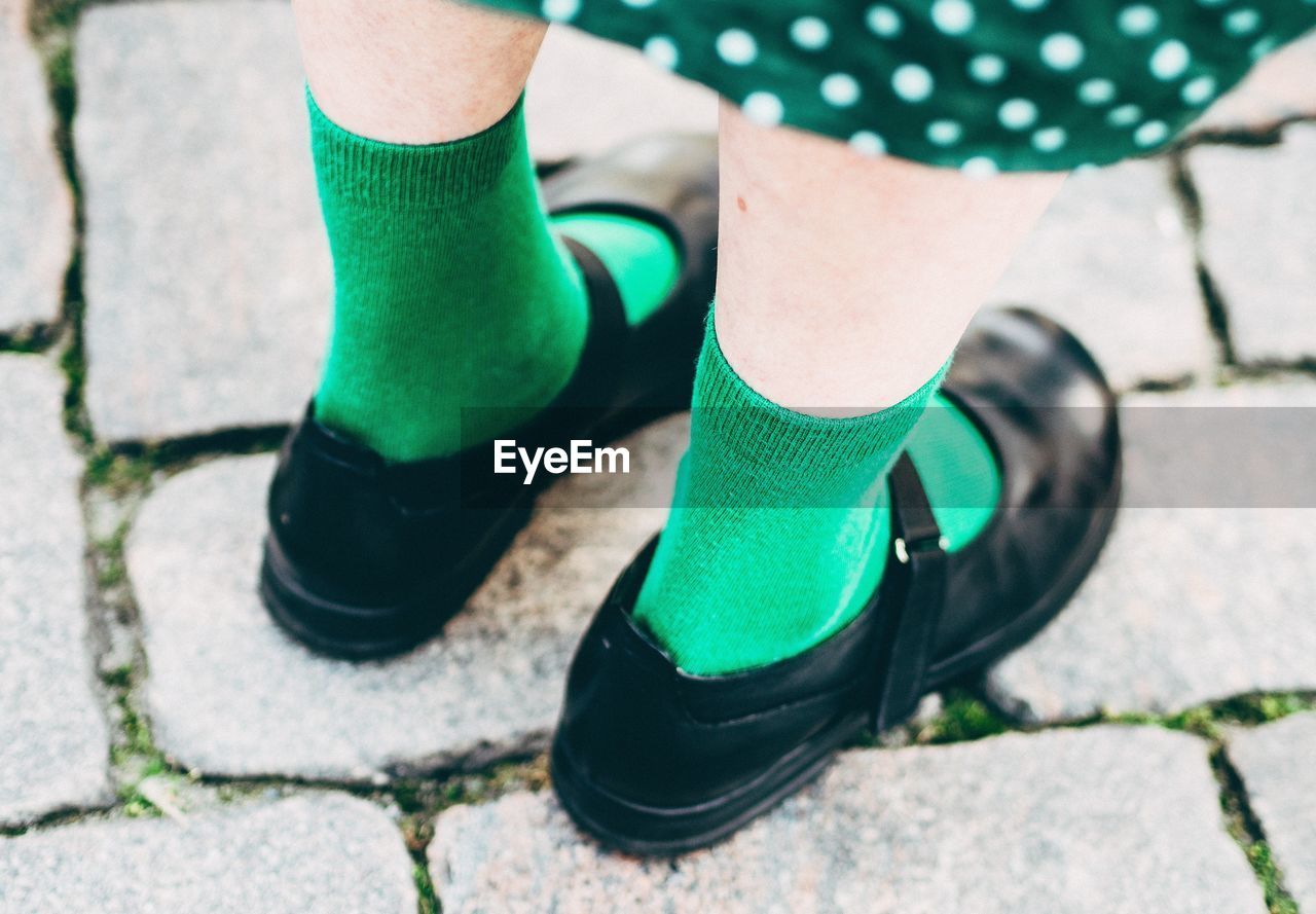 Low section of girl wearing shoes on street