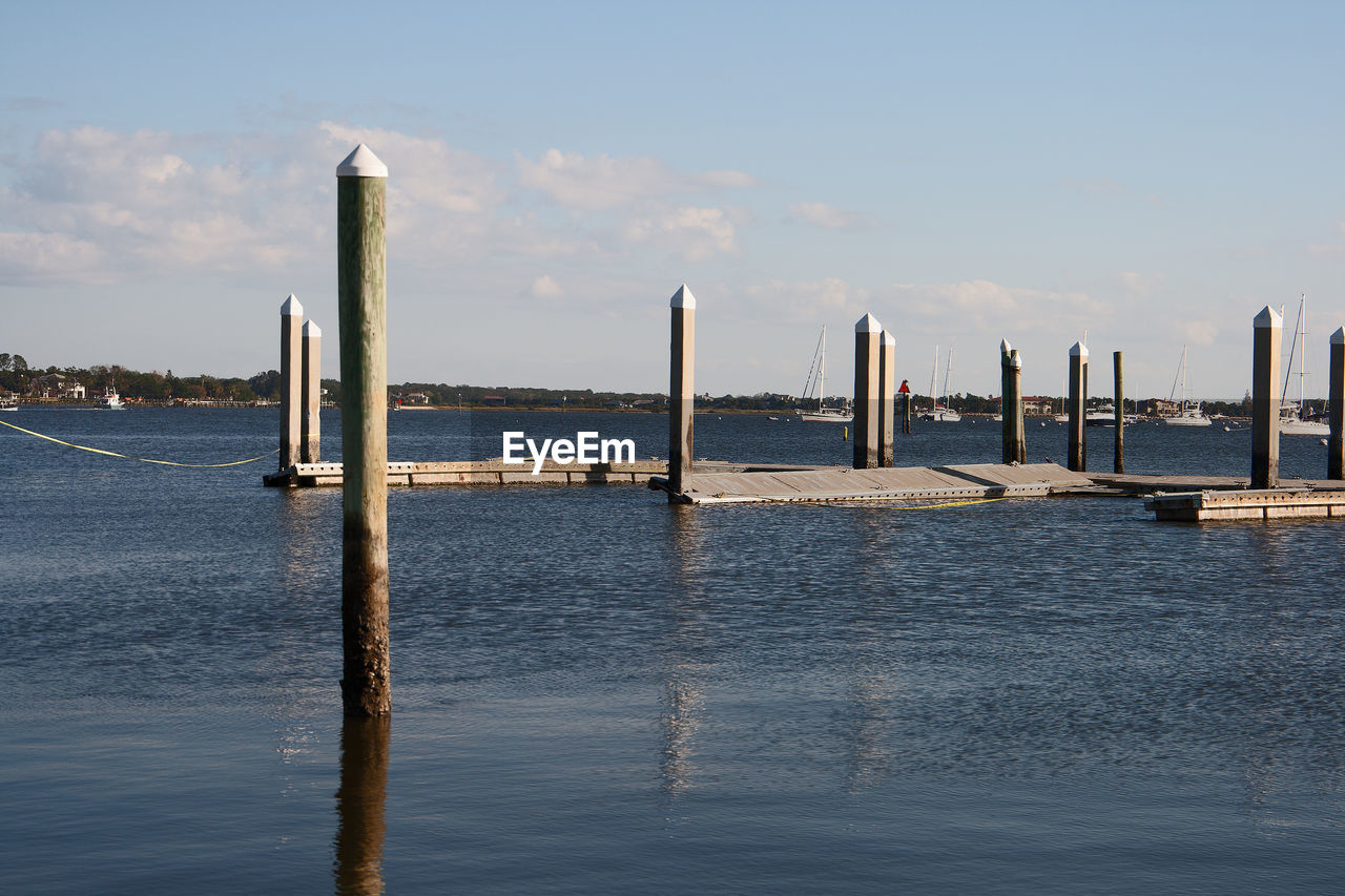 WOODEN POST IN SEA AGAINST SKY