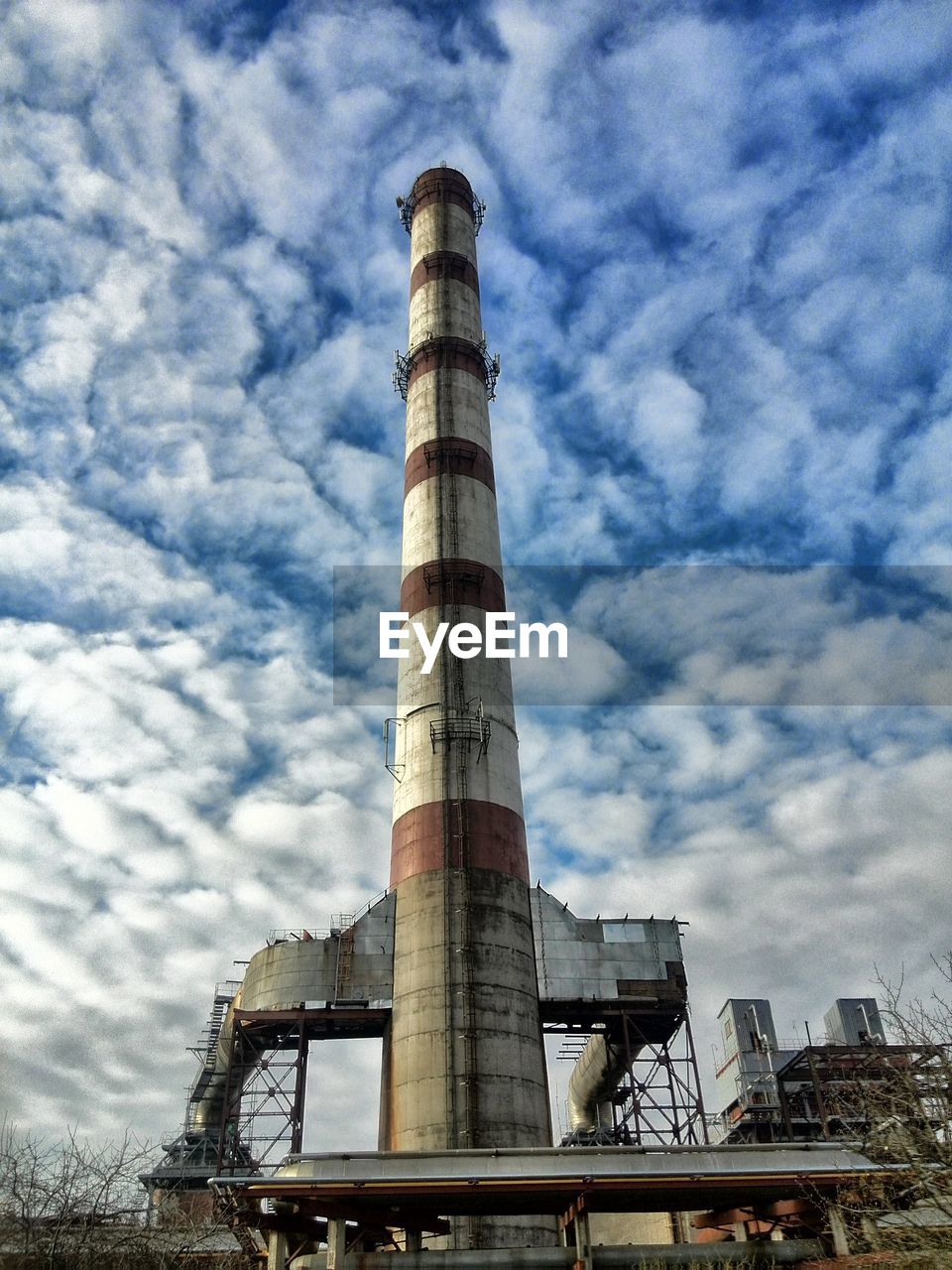 Low angle view of smoke stack against cloudy sky