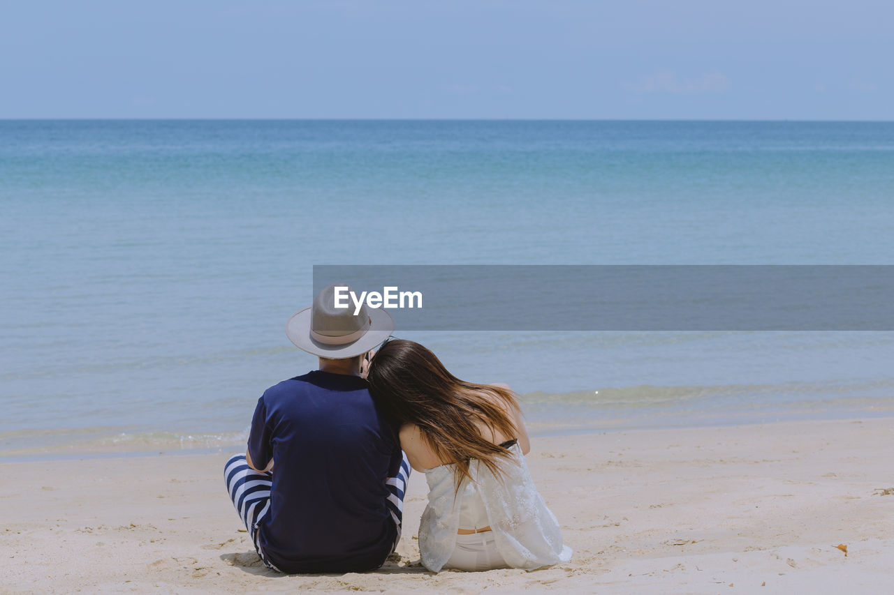 Rear view of couple sitting at beach