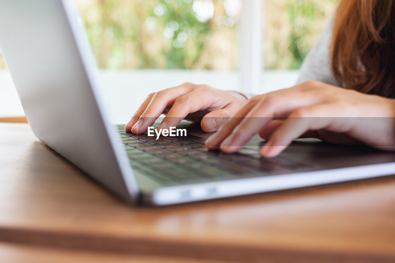 midsection of woman using laptop on table