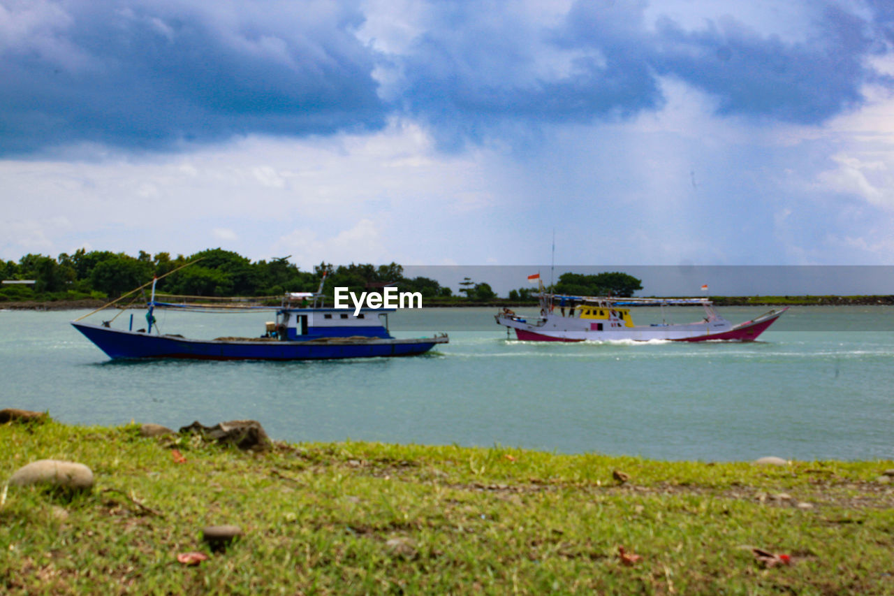 BOAT MOORED ON SEA AGAINST SKY