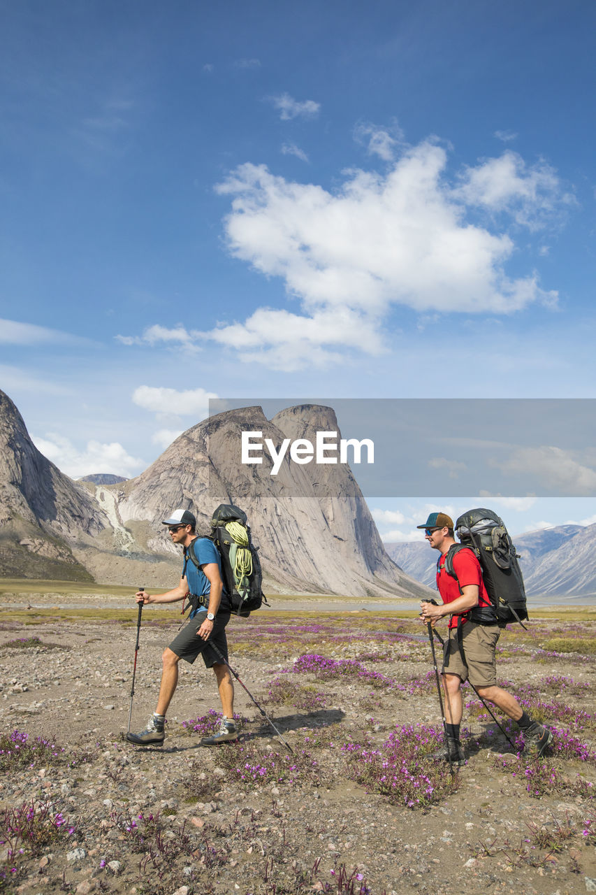 Two backpackers hiking through alpine meadow, akshayak pass