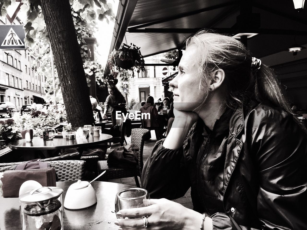 Thoughtful woman sitting at sidewalk cafe