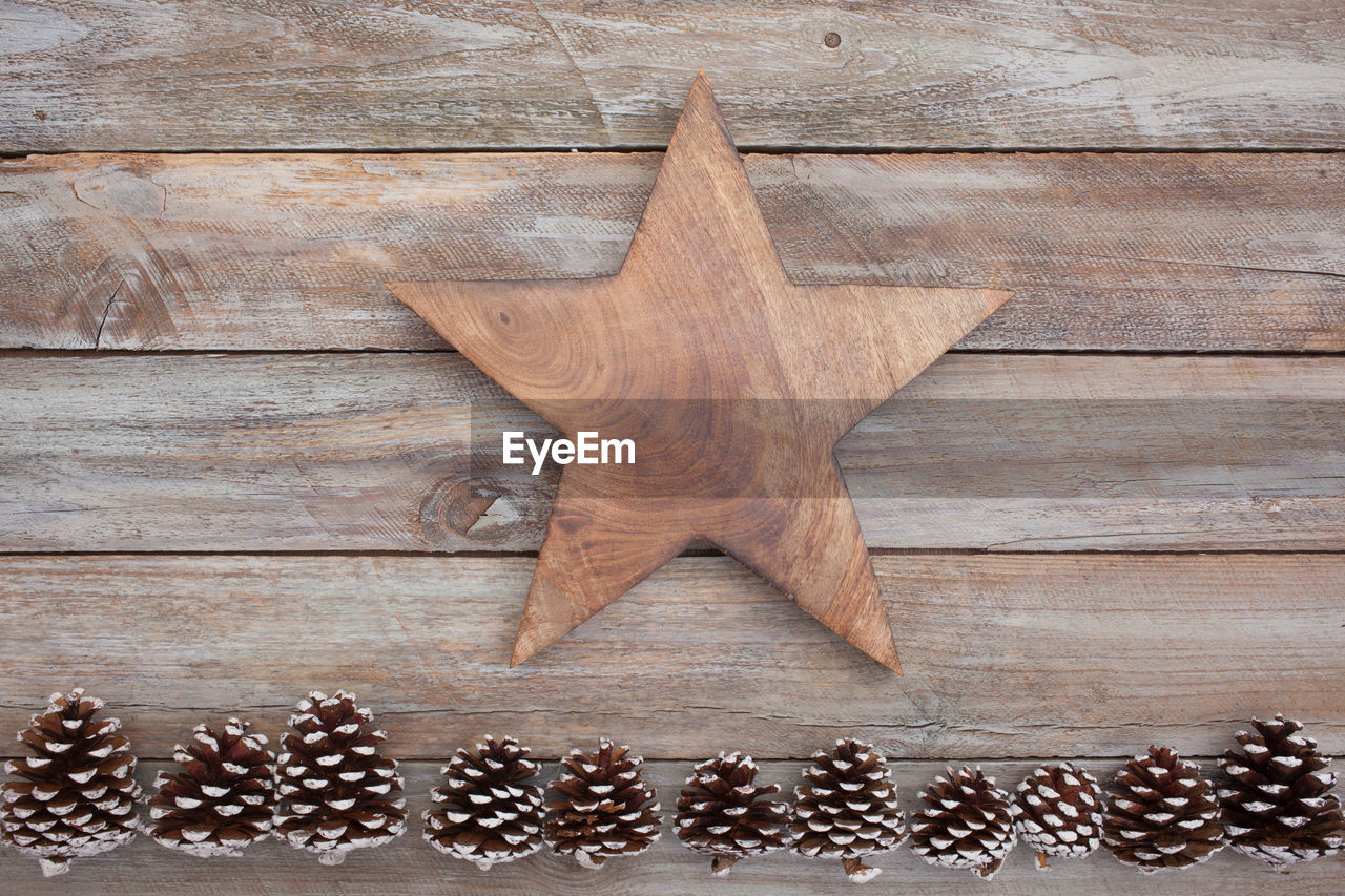 Directly above shot of wooden star with pine cones on table