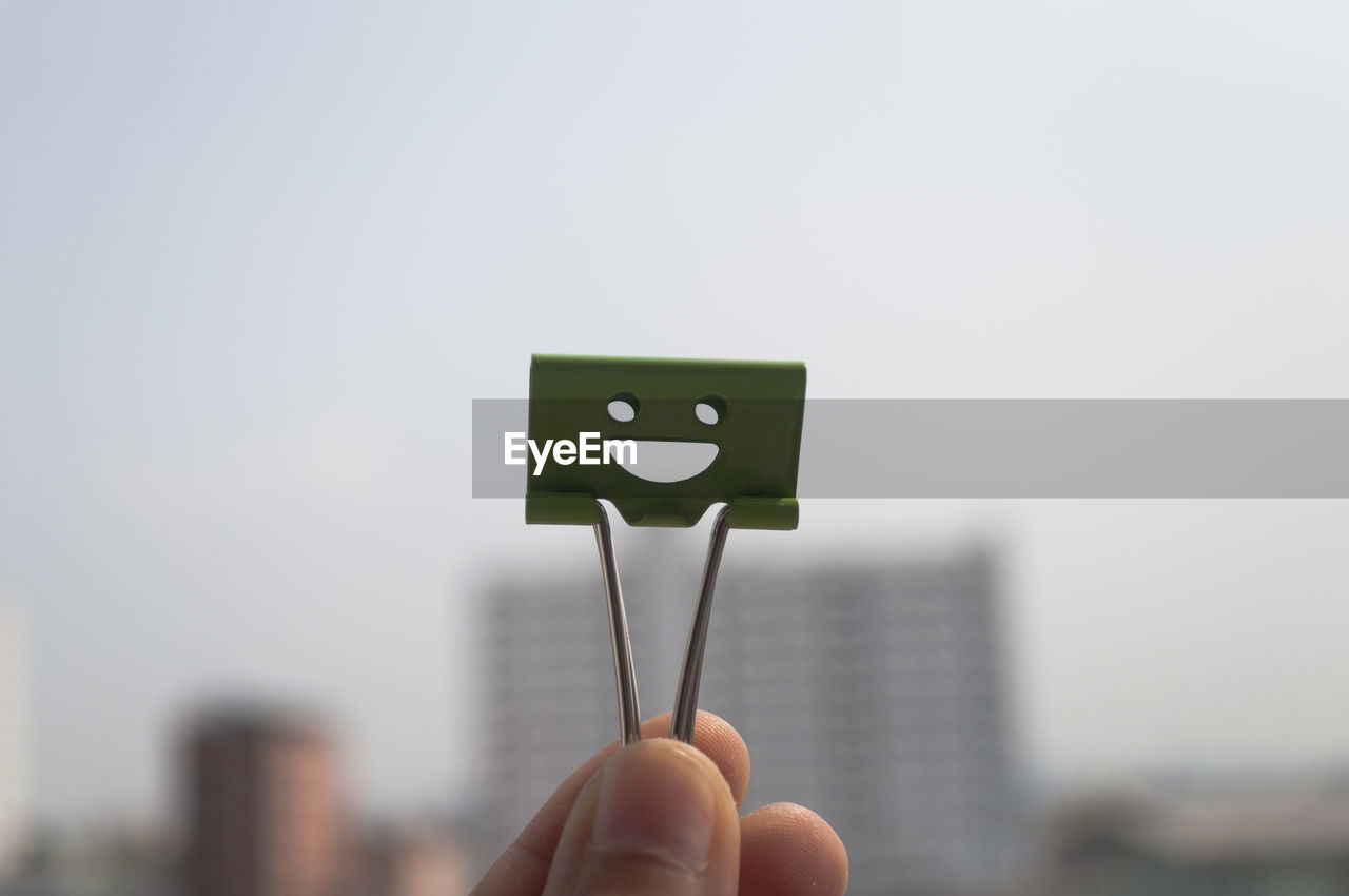 Close-up of hand holding clip against clear sky