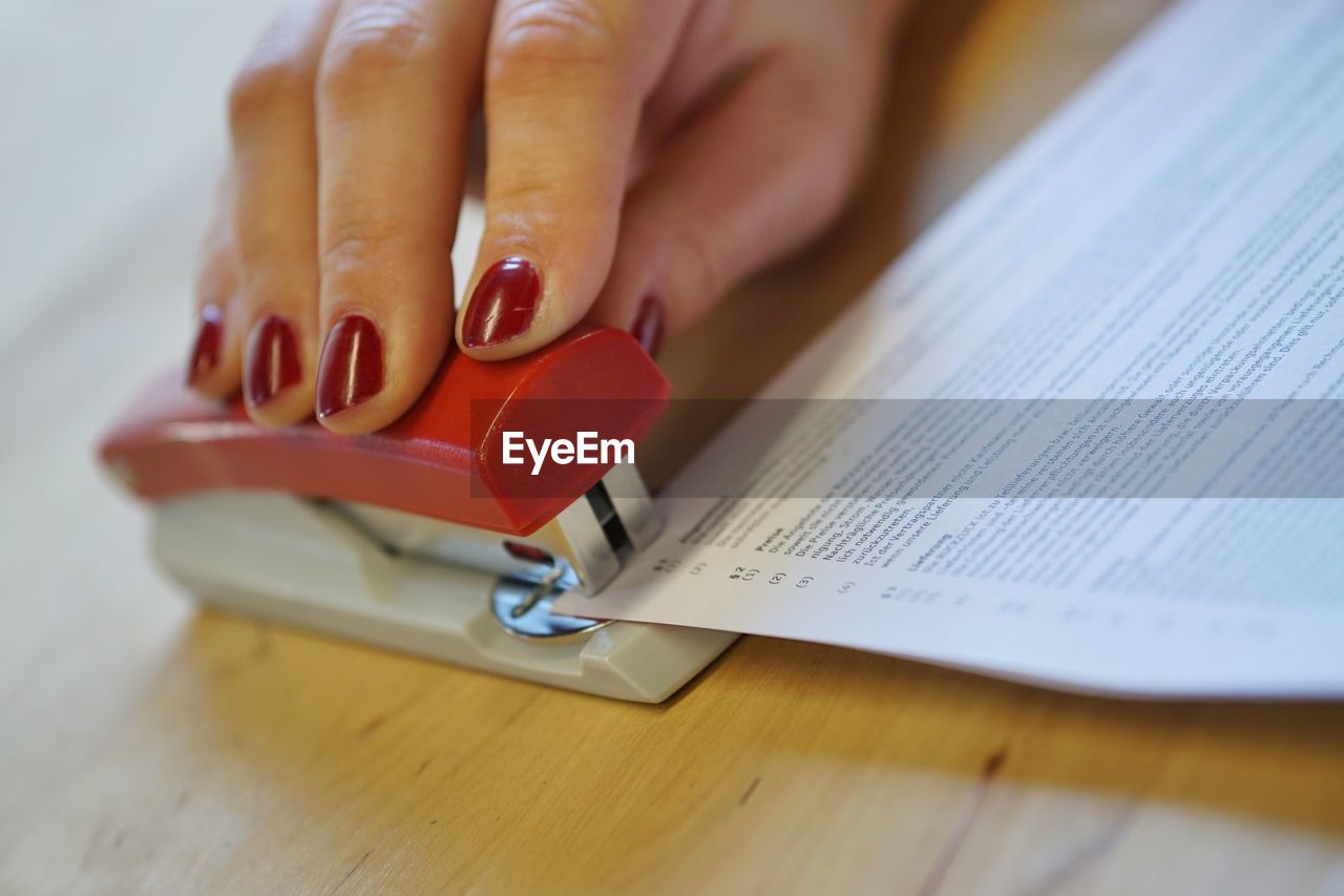 Close-up of woman stapling documents on table