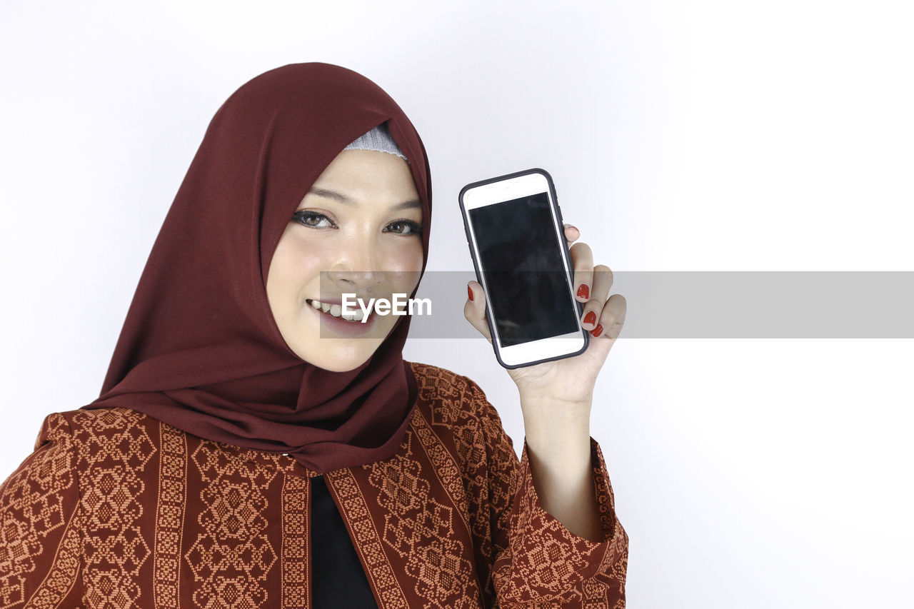 PORTRAIT OF SMILING YOUNG WOMAN USING PHONE