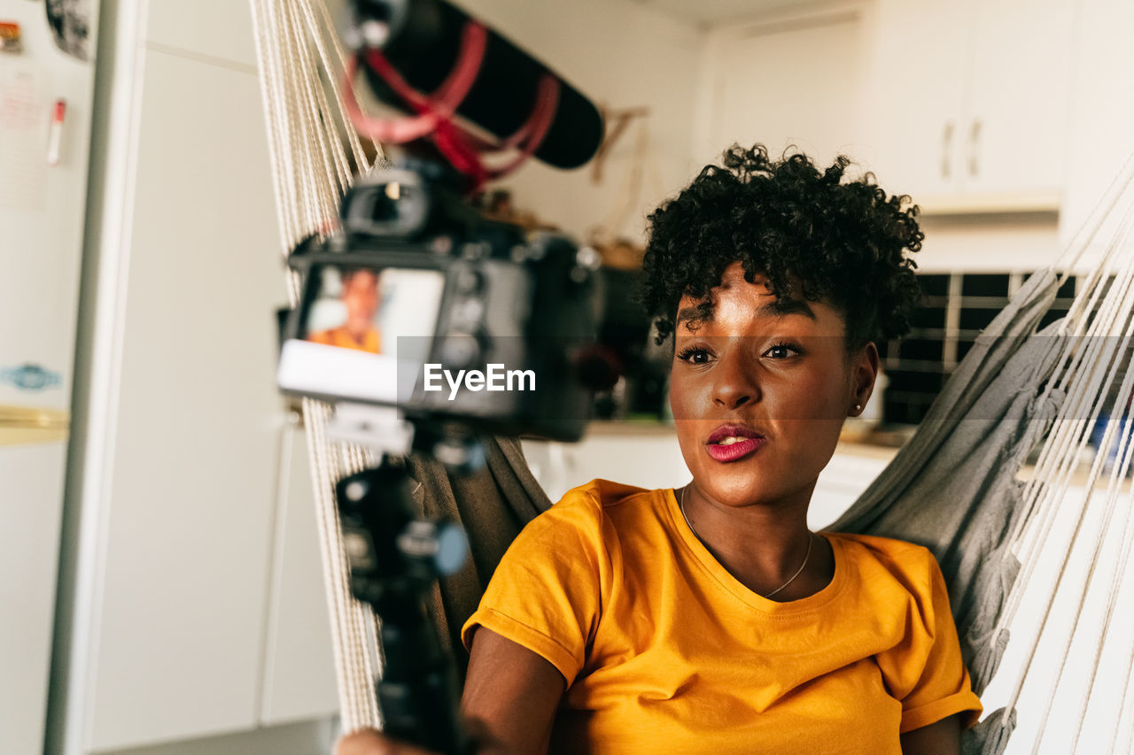 Cheerful young african american female blogger recording video while preparing content for social networks at home