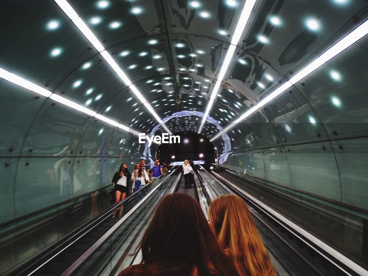 People on escalators against illuminated ceiling