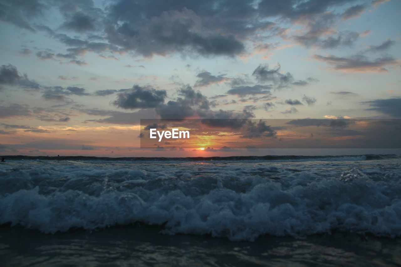 Scenic view of sea against dramatic sky during sunset