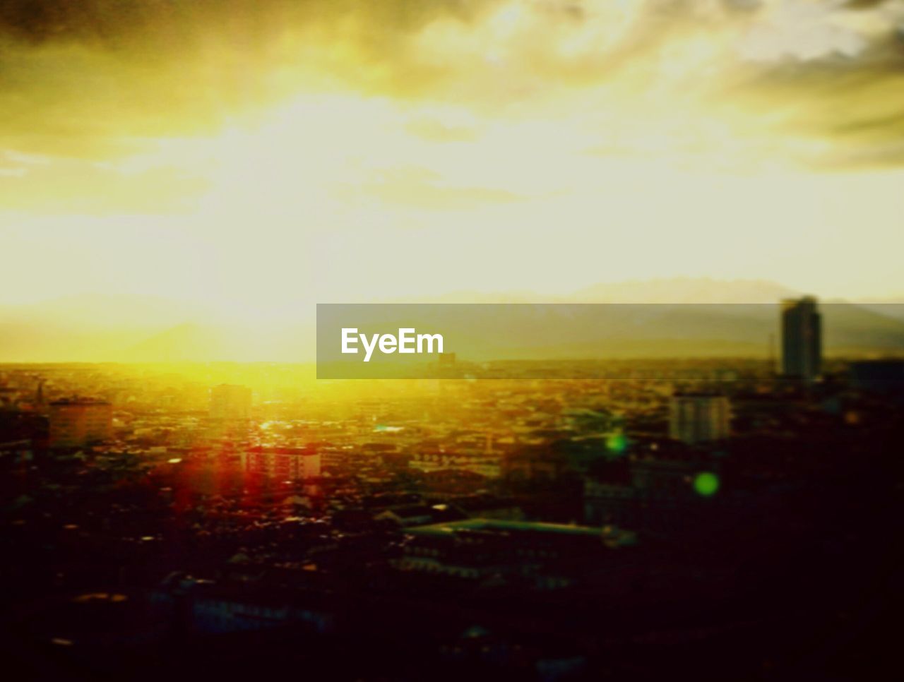 Buildings in city against cloudy sky during sunset