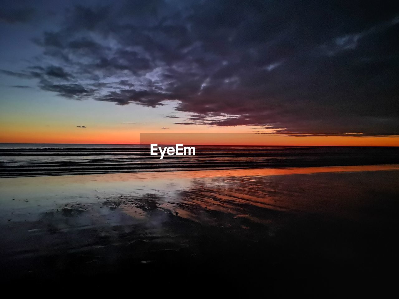 SCENIC VIEW OF BEACH AGAINST DRAMATIC SKY