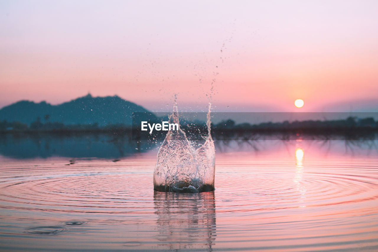 Close-up of water splashing in lake against sky during sunset