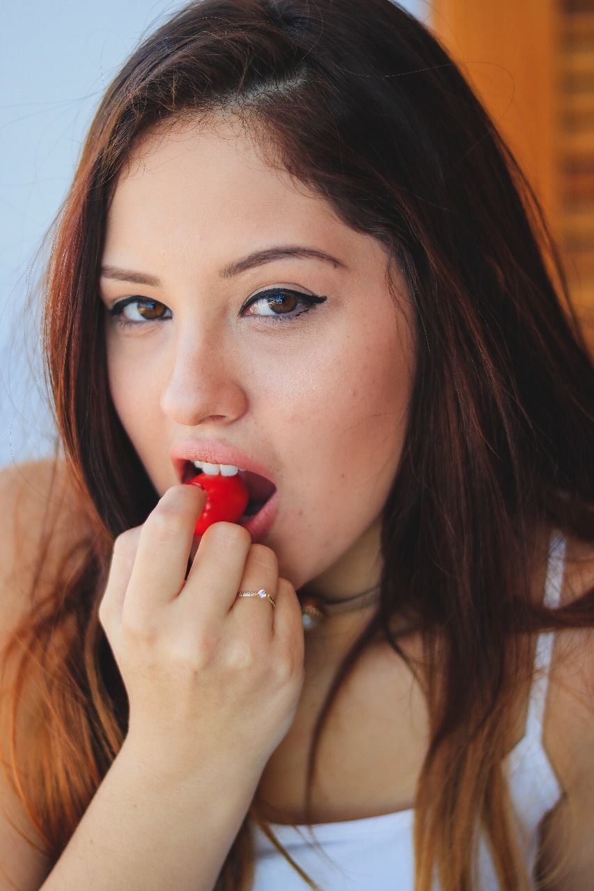 Close-up portrait of young woman eating berry