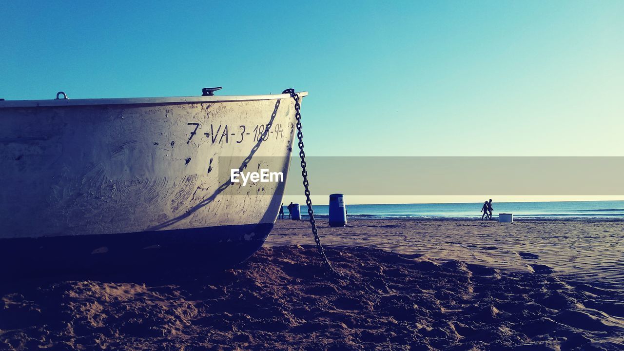 Boat moored at beach against clear sky