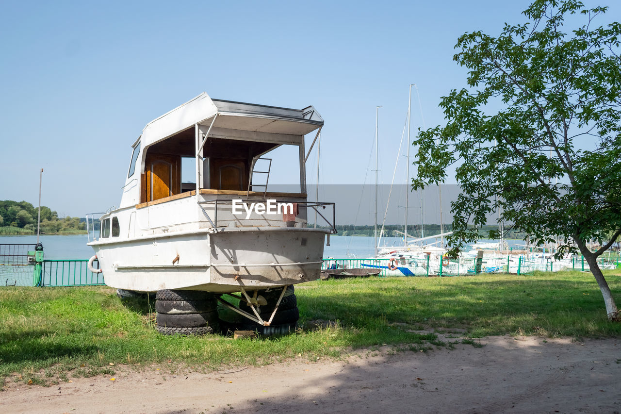 Old sailing yacht on land. old white motor yacht beached at a dock for painting and repair