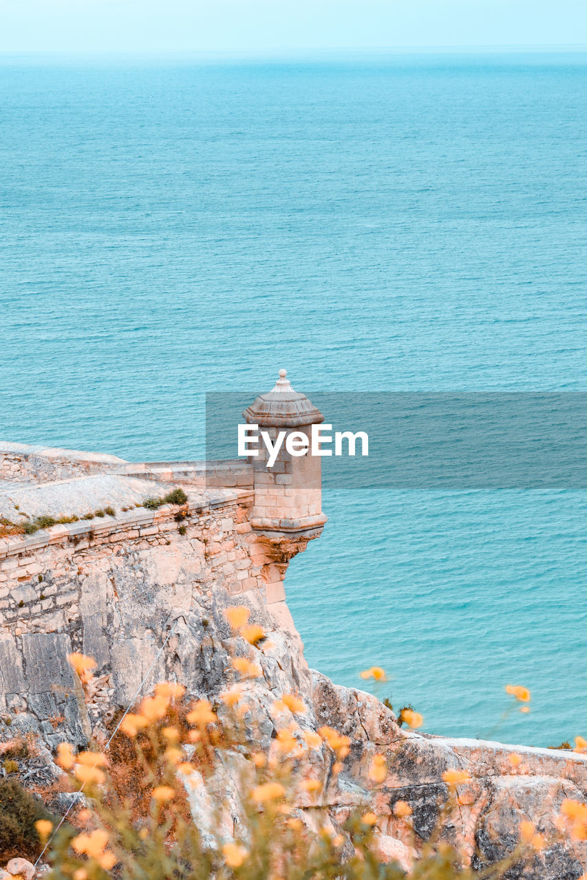 Scenic view of sea against sky and small tower