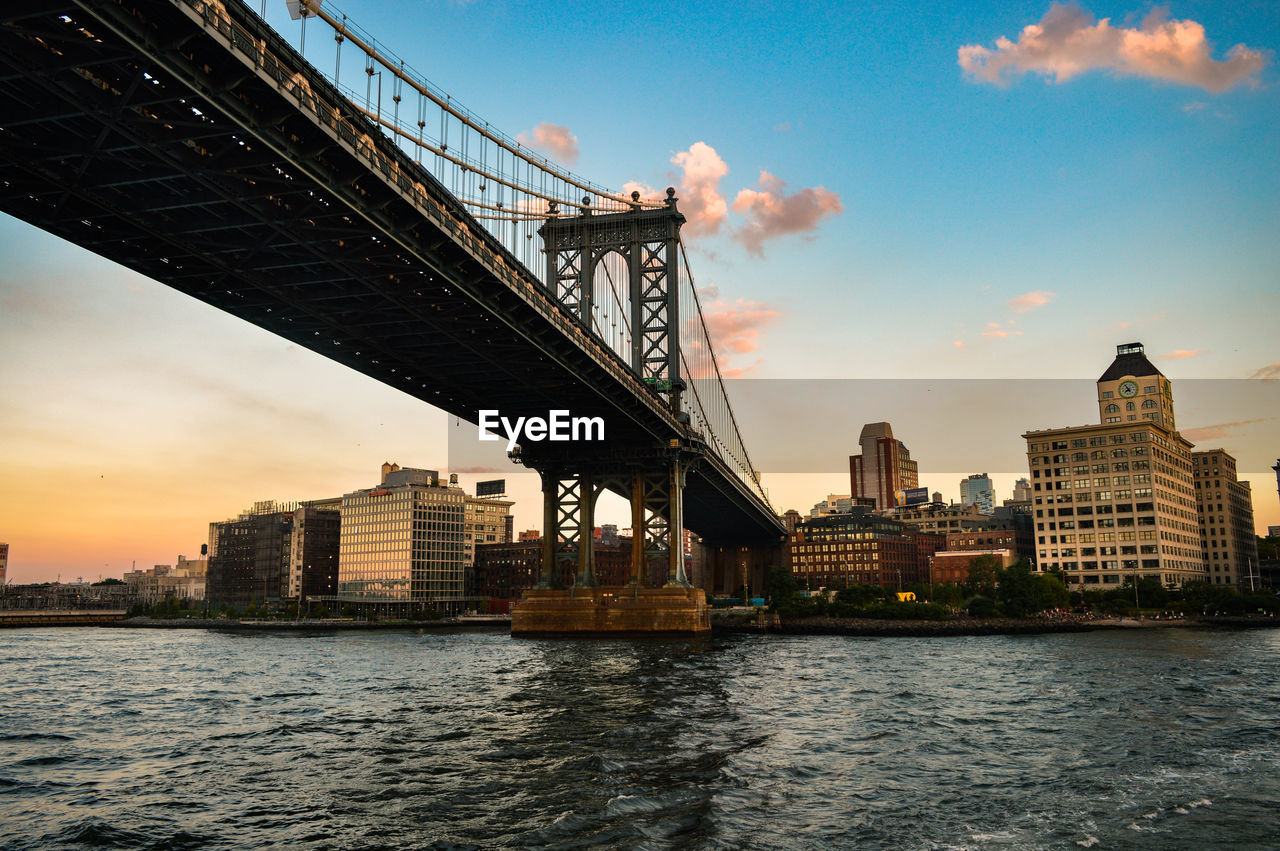 View of suspension bridge in city at sunset