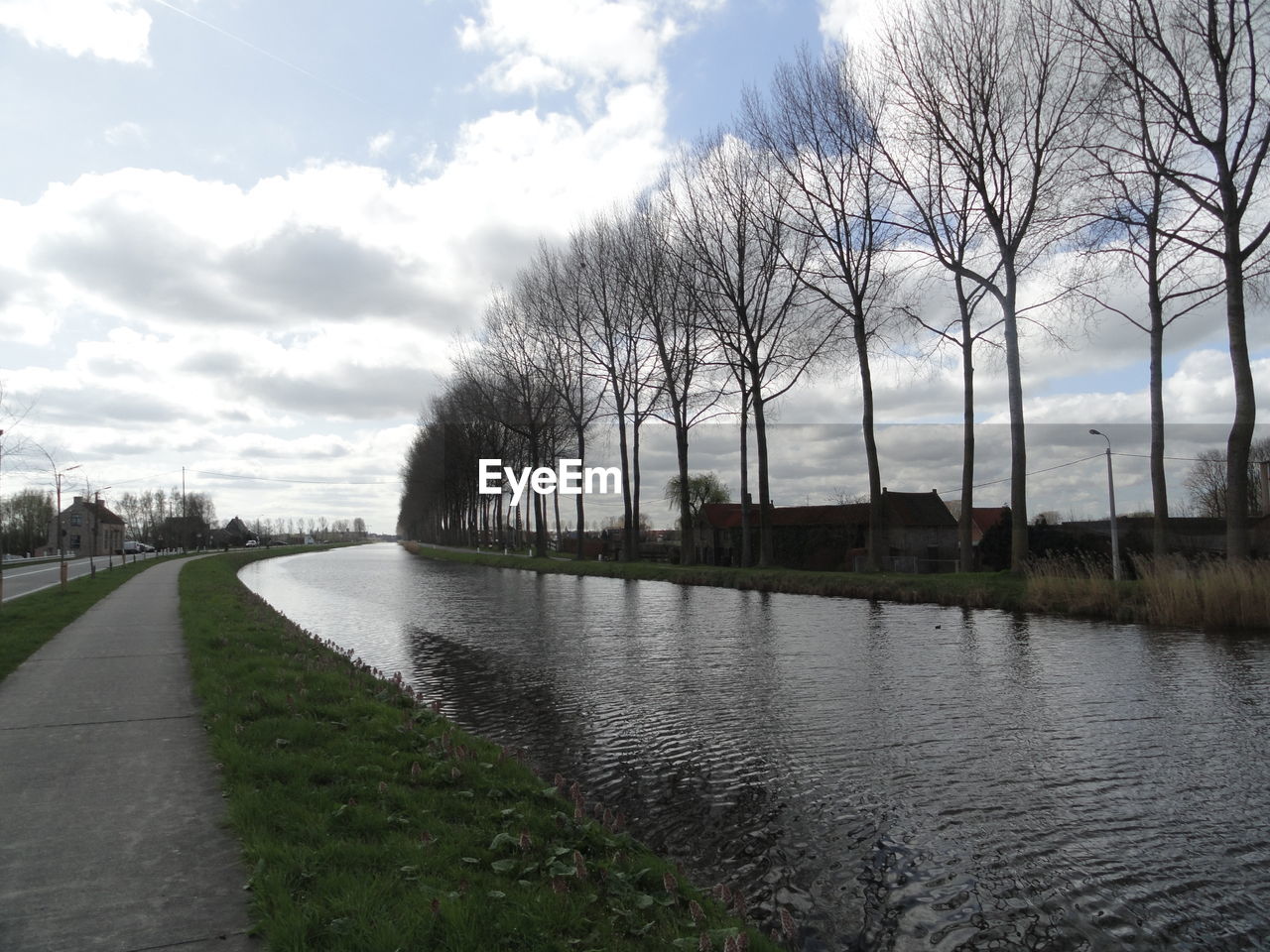 River by bare trees against sky