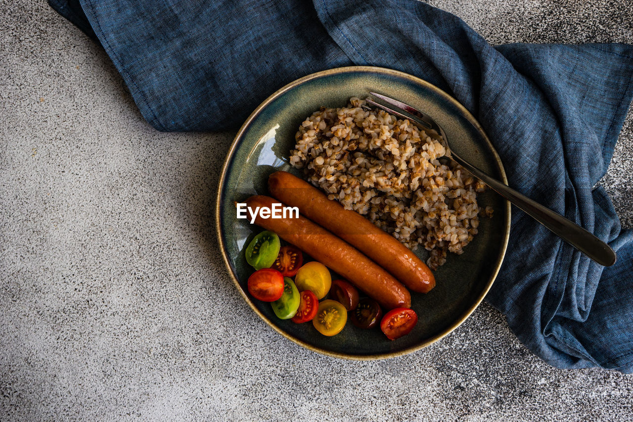 Healthy breakfast with buckwheat, sausages and cherry tomatoes in a bowl