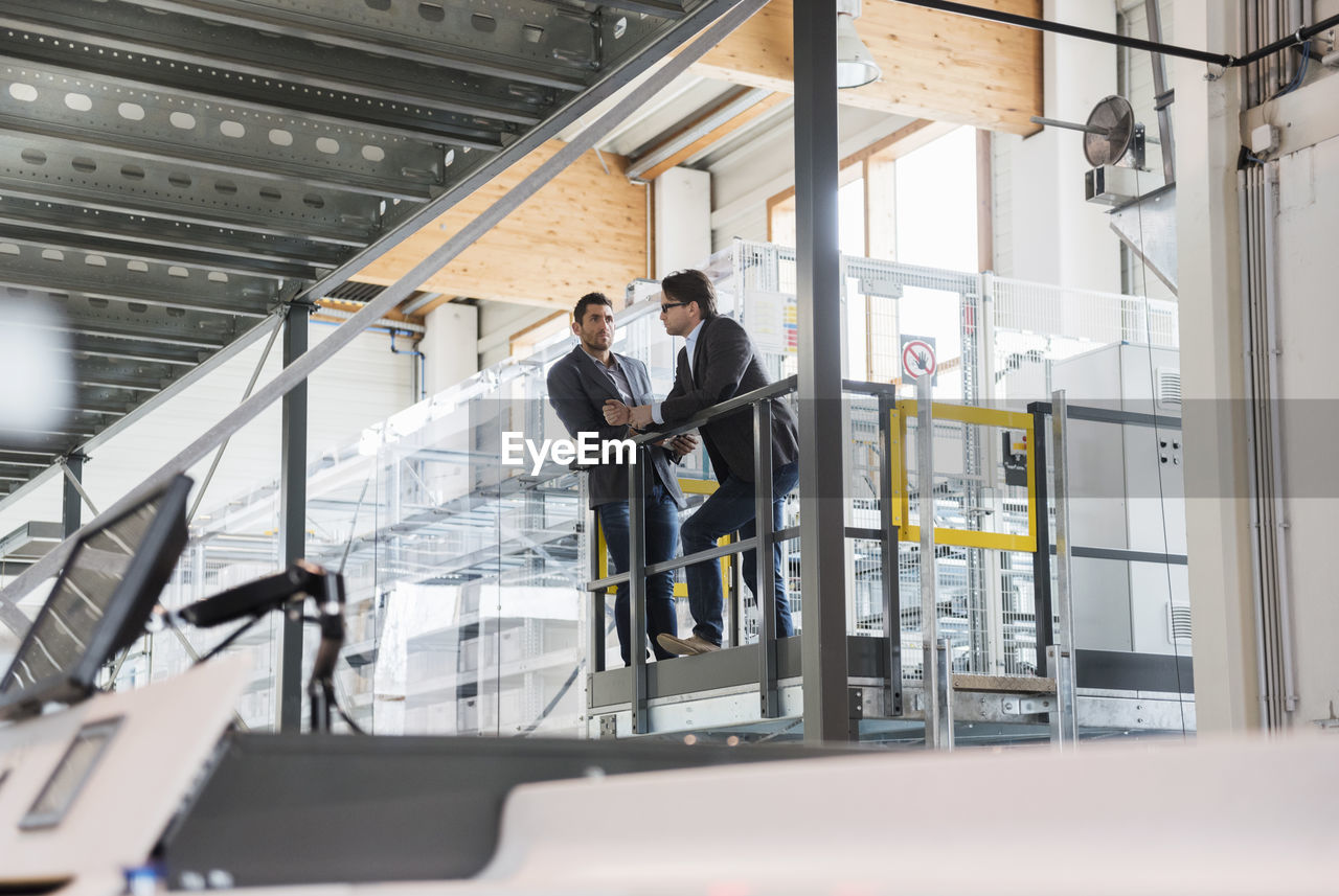 Two businessmen talking in modern factory