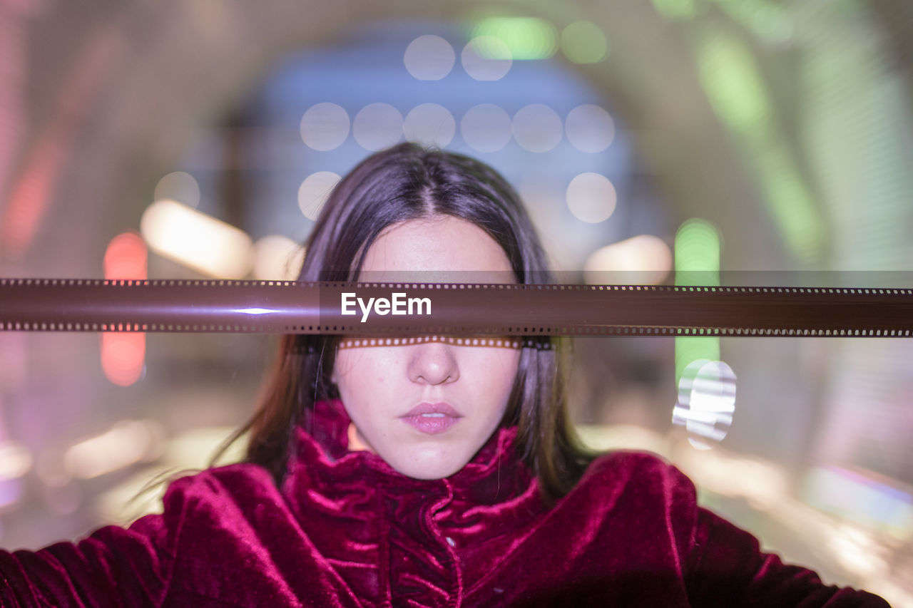 Woman holding film negative over eyes