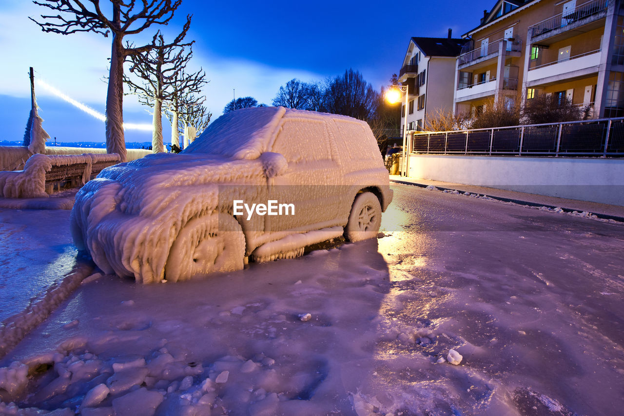 Snow covered vehicle by bare trees