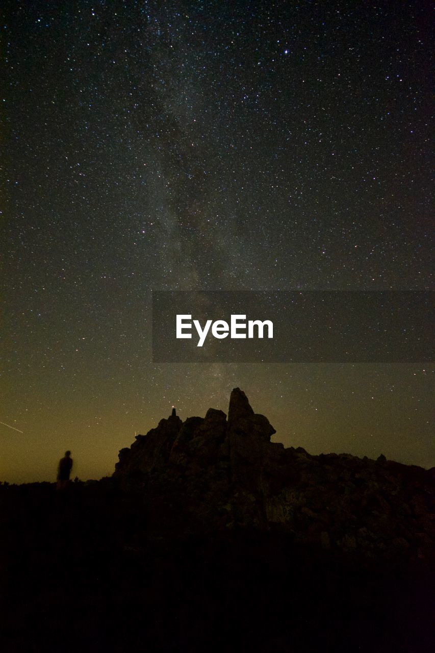 Low angle view of silhouette rock formation against sky at night