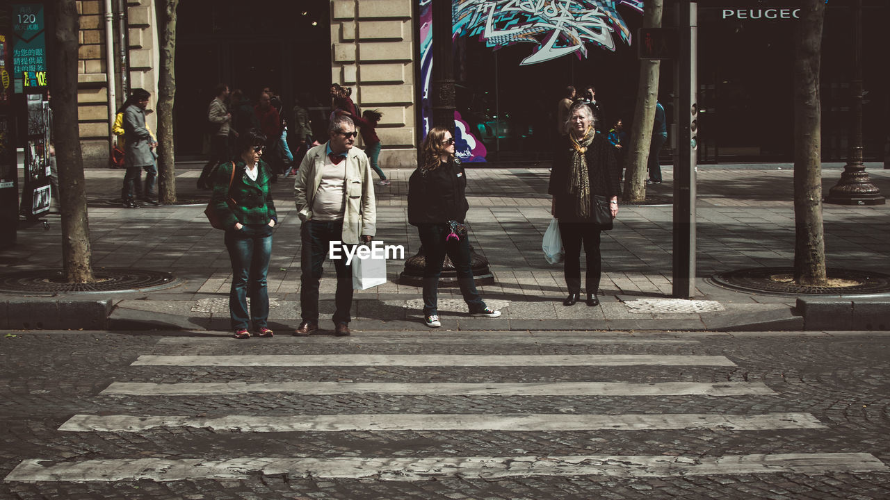 PEOPLE WALKING ON ROAD WITH BUILDINGS IN BACKGROUND