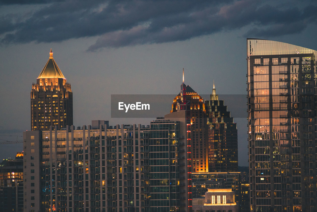 Illuminated cityscape against sky during sunset