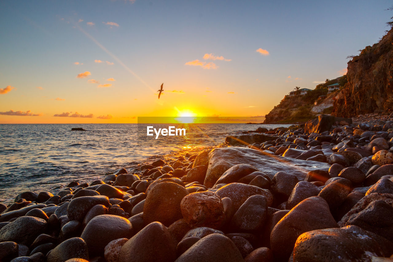 Close-up of pebbles on beach against sky during sunset