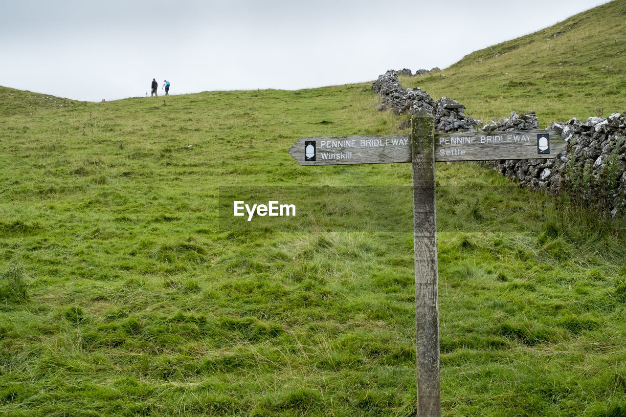 Sign on grassy field against sky