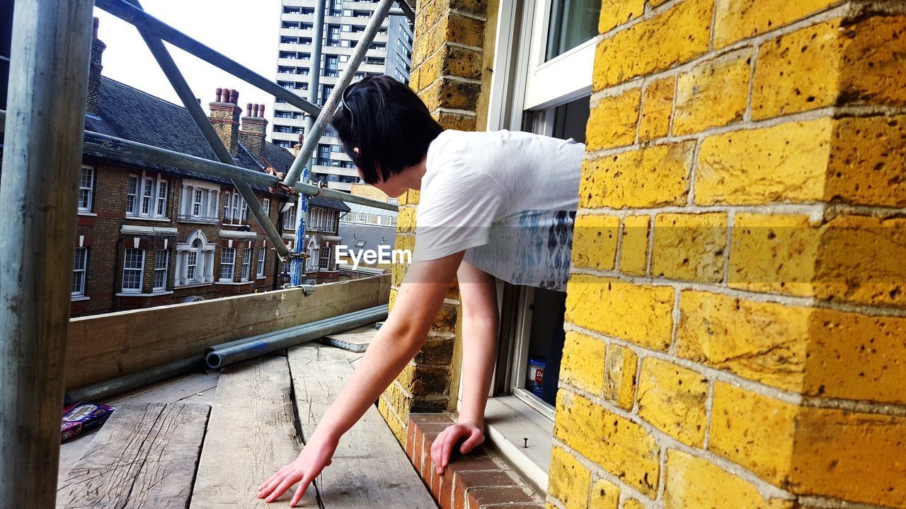 FULL LENGTH OF WOMAN STANDING AGAINST BUILT STRUCTURES