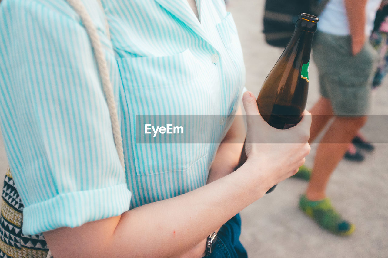 Midsection of woman holding beer