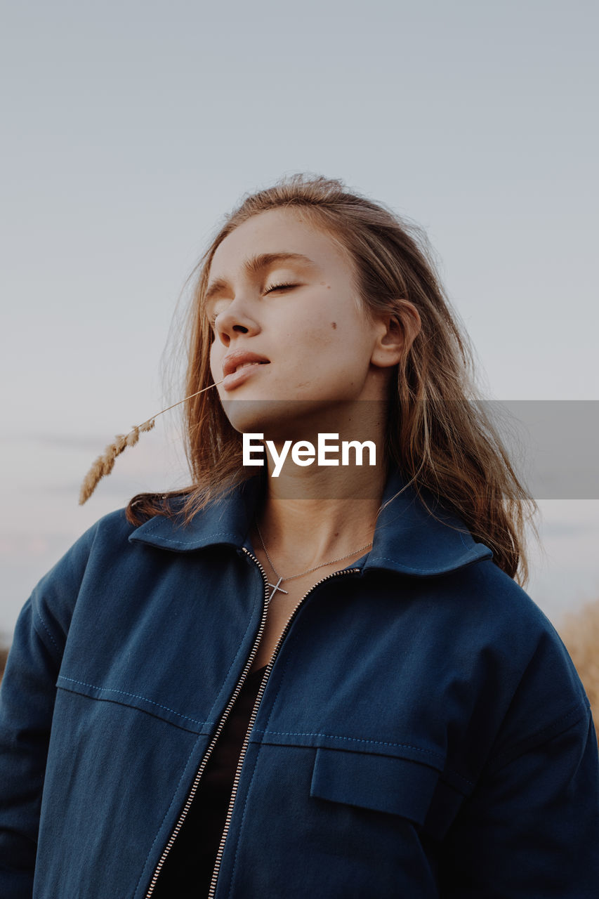 Beautiful young woman with eyes closed against sky