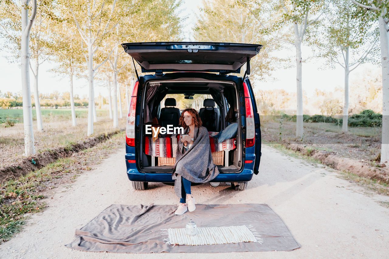 Woman holding mug while sitting in camper trailer