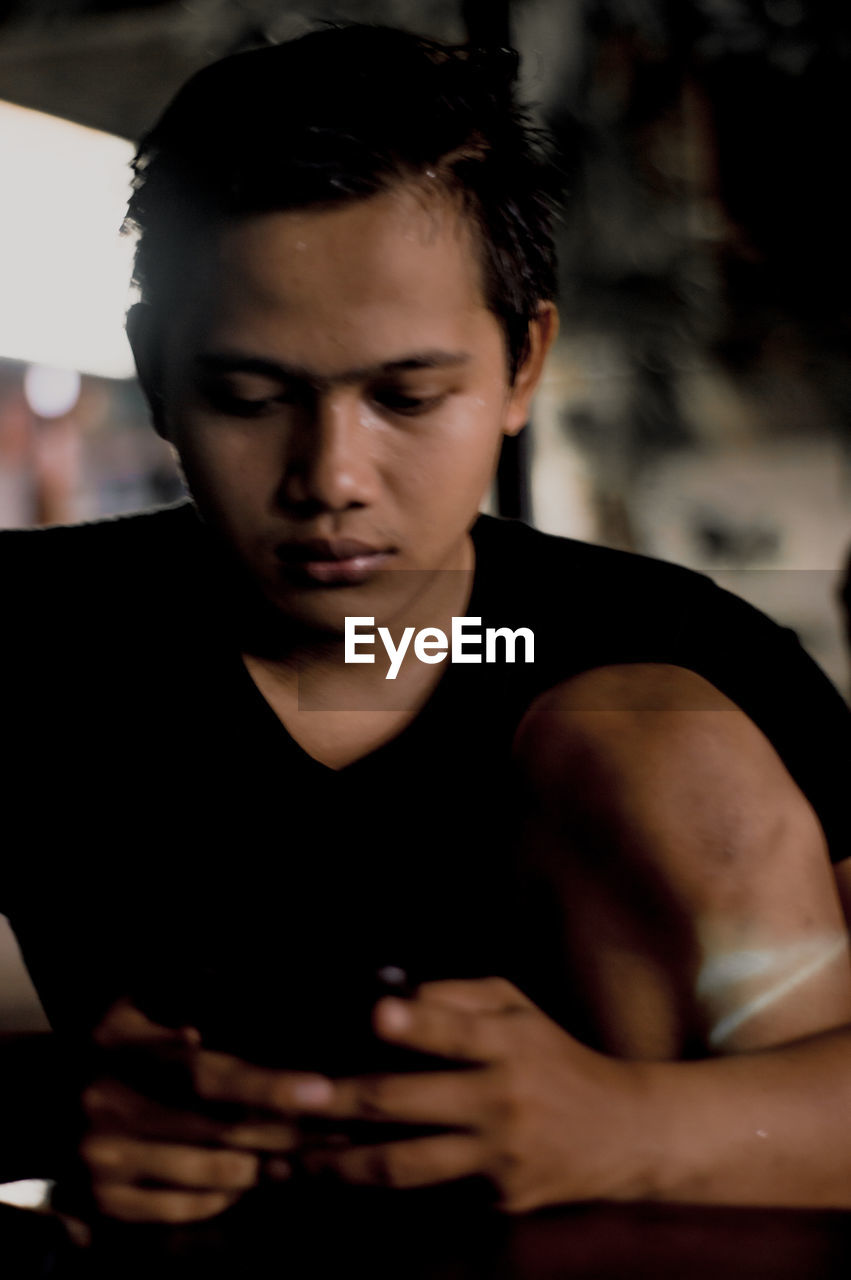 PORTRAIT OF YOUNG MAN LOOKING THROUGH CAMERA